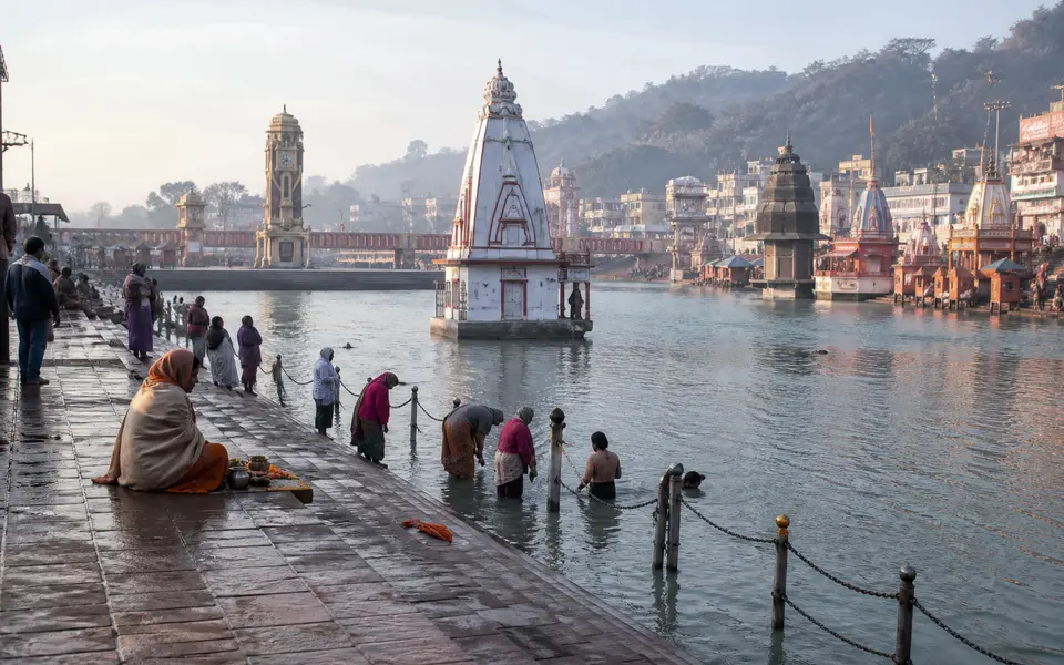 Early morning scene at Har Ki Pauri ghat in Haridwar with pilgrims offering prayers and taking a dip in the Ganga.