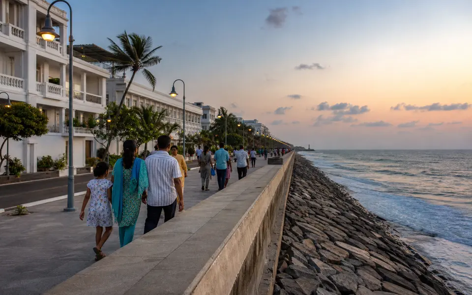 Evening view of Pondicherry’s seaside promenade with families walking along the sea wall beside the Bay of Bengal.