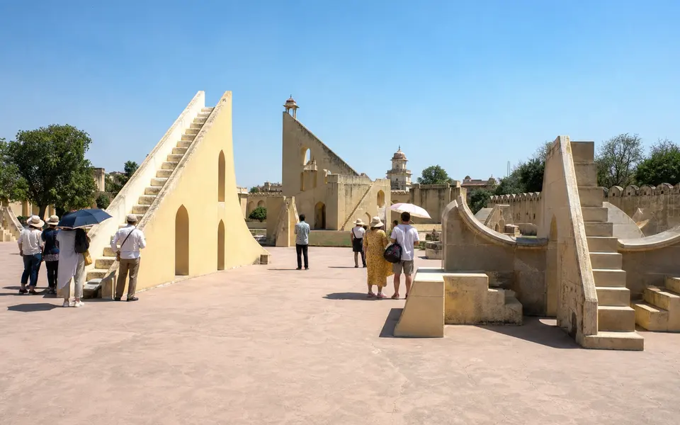Stone astronomical instruments at Jantar Mantar in Jaipur with visitors walking among them under a bright midday sky.