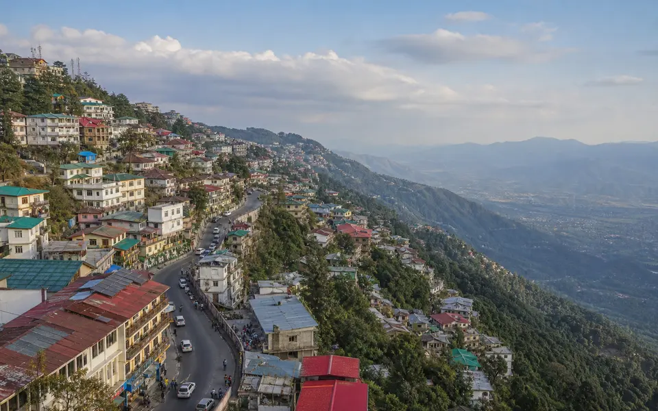 Ridge-top view of Mussoorie town with buildings along the hill and the valley dropping away on one side.