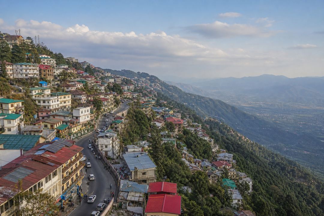Ridge-top view of Mussoorie town with buildings along the hill and the valley dropping away on one side.