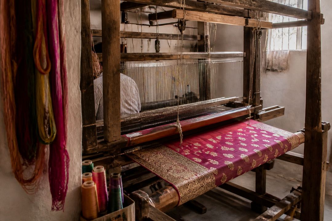A Banarasi weaver working at a handloom with colourful silk threads in Varanasi.