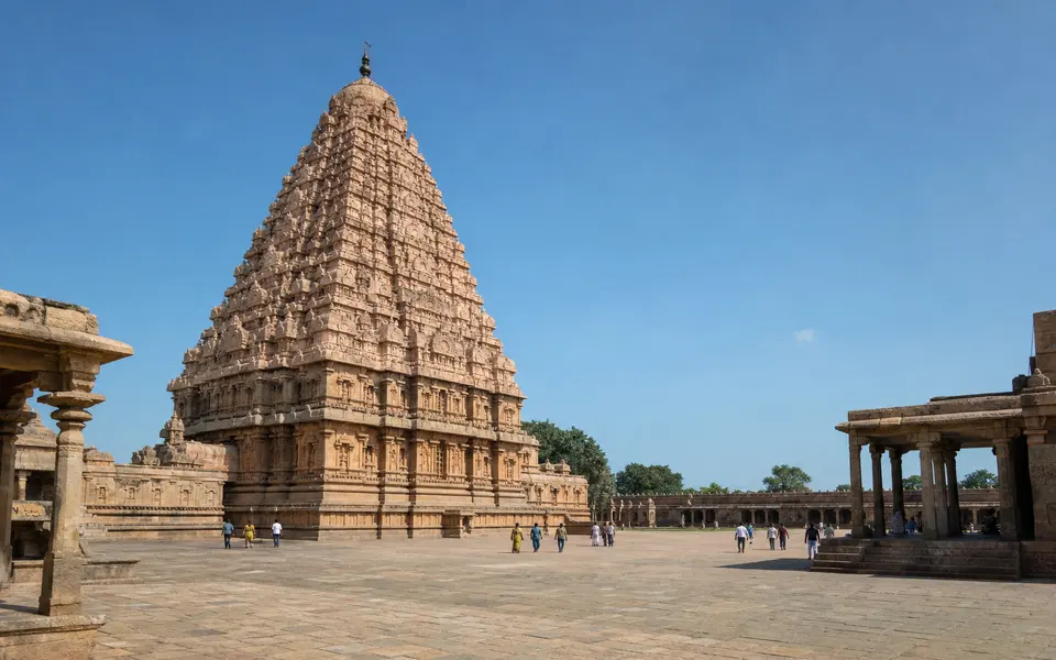 Wide-angle view of the towering vimana of Gangaikonda Cholapuram temple with a spacious stone courtyard in front.