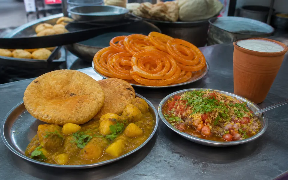 Plates of kachori-sabzi, jalebi and tamatar chaat on a street-food counter in Varanasi.