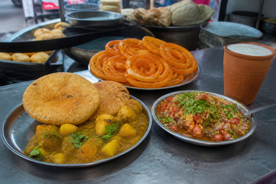 Plates of kachori-sabzi, jalebi and tamatar chaat on a street-food counter in Varanasi.