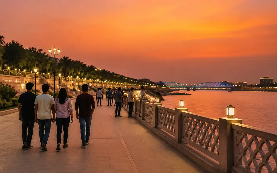 Friends walking along the Gomti Riverfront promenade at sunset with the river and lights in the background.