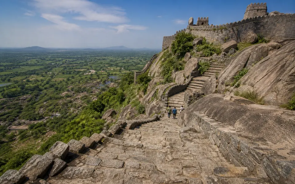 Steep stone steps leading up a rocky hill at Gingee Fort with ramparts and wide views of the Tamil Nadu countryside