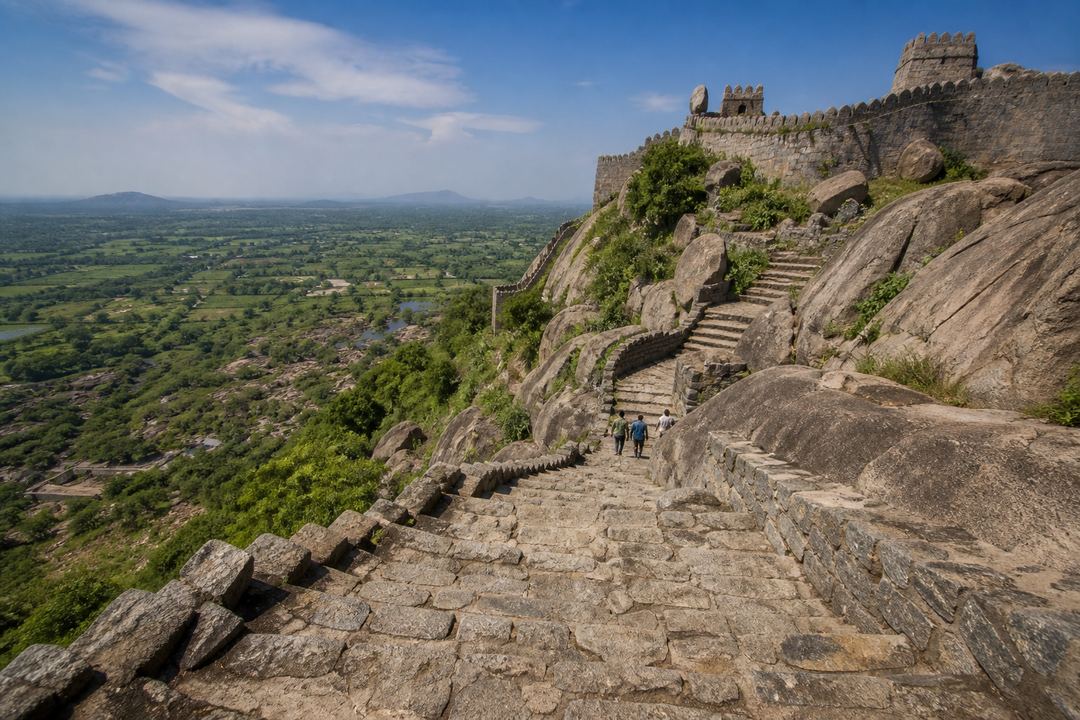Steep stone steps leading up a rocky hill at Gingee Fort with ramparts and wide views of the Tamil Nadu countryside