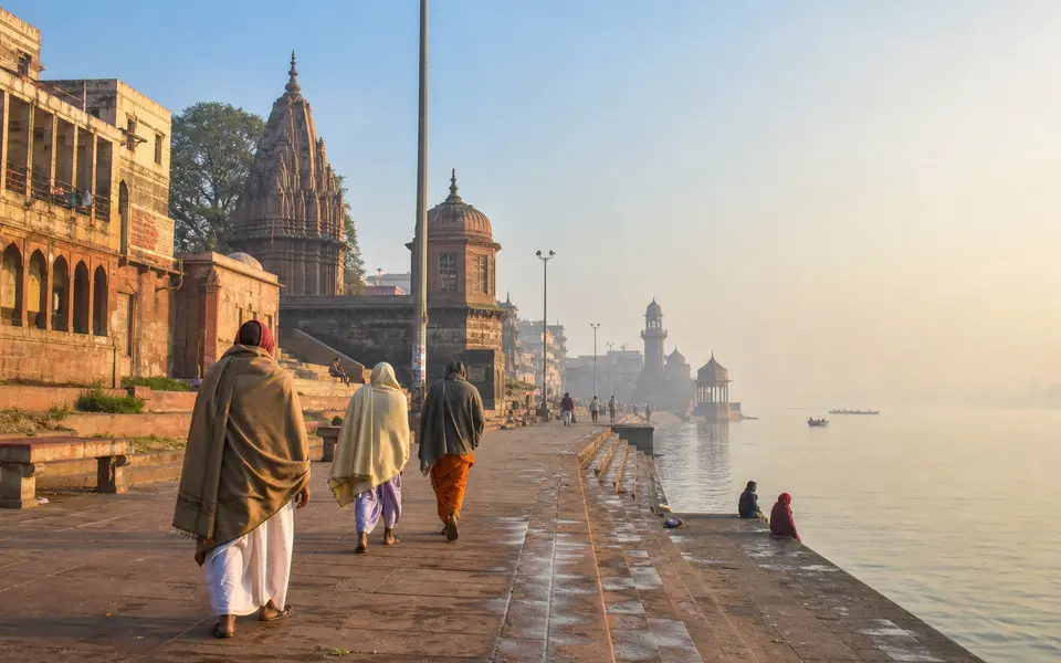 Winter morning at a riverside ghat in Mathura with soft sunlight and pilgrims walking along the steps.