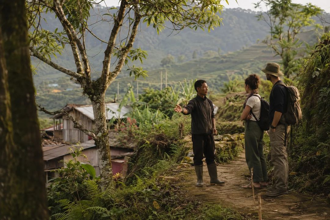 A local guide explains forest and village stewardship to two visitors in Northeast India.