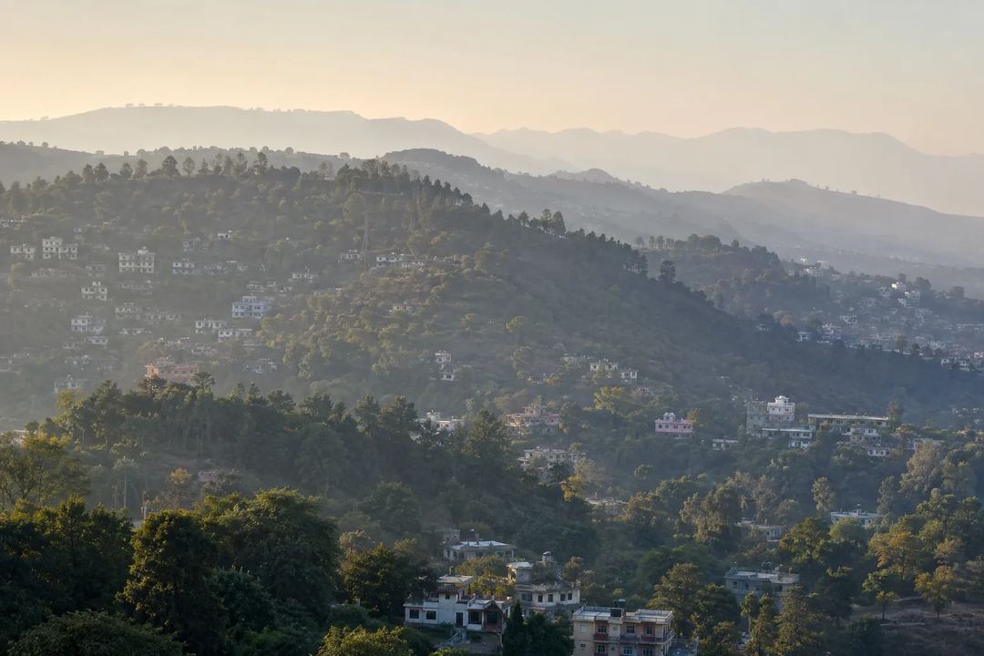 Jammu's wooded Shivalik foothills and urban edge in soft winter morning haze.