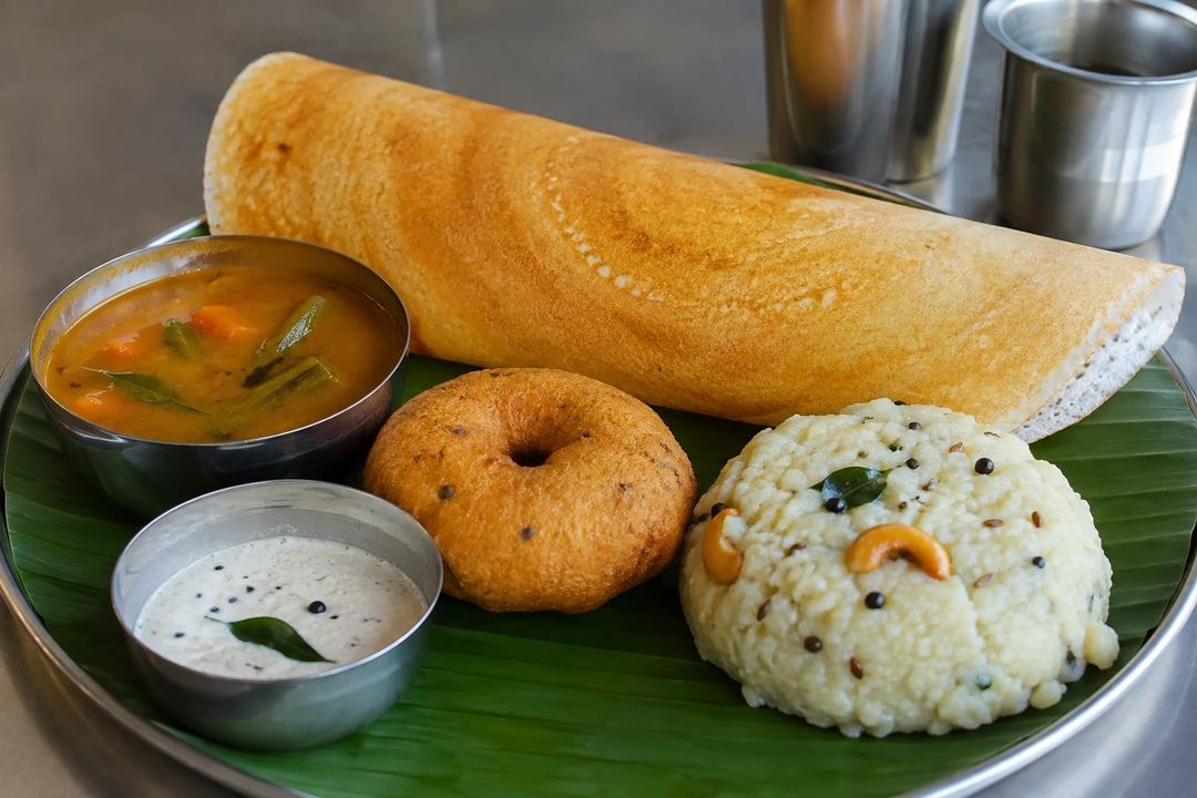 Crisp dosa medu vada and ven pongal served with sambar and coconut chutney