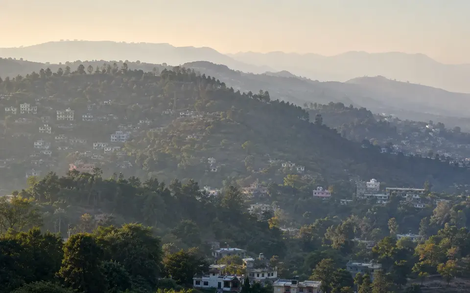 Jammu's wooded Shivalik foothills and urban edge in soft winter morning haze.