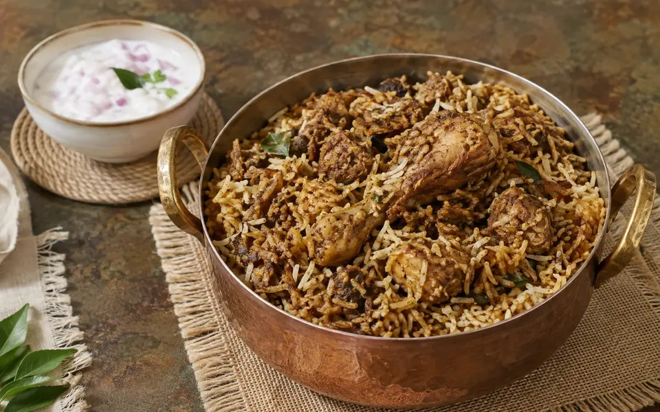 Ulavacharu chicken biryani with a dark horse gram coating and a small bowl of onion raita