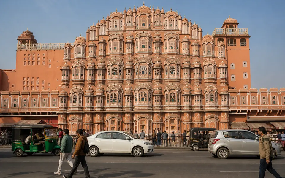 Street-level view of Jaipur’s Hawa Mahal with people walking and light traffic in front on a sunny winter afternoon.