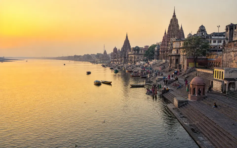 Yamuna riverfront in Mathura at sunrise with temple spires and ghats along the bank.