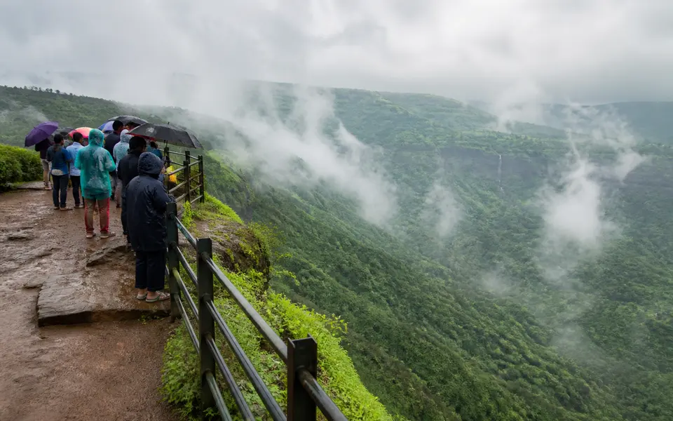 Clifftop viewpoint near Lonavala with green Western Ghats valleys and low monsoon clouds.