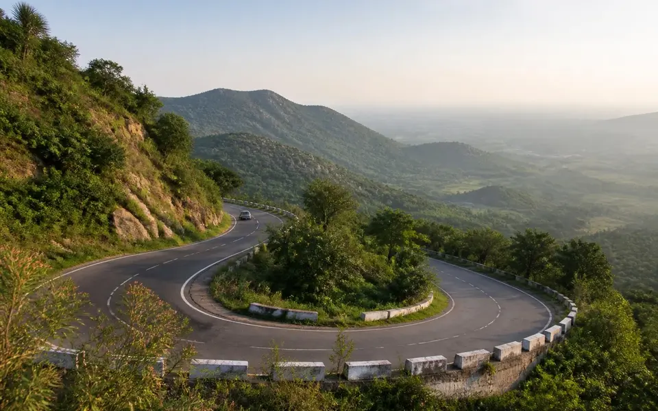 Reference-led landscape illustration of a sweeping hairpin bend on the green Eastern Ghats road to Yelagiri, with a hazy valley beyond.
