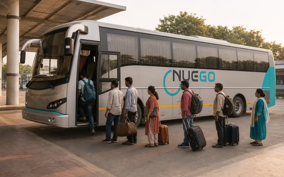 Passengers boarding a clearly branded NueGo electric intercity coach for a Varanasi journey at an Indian bus terminal.