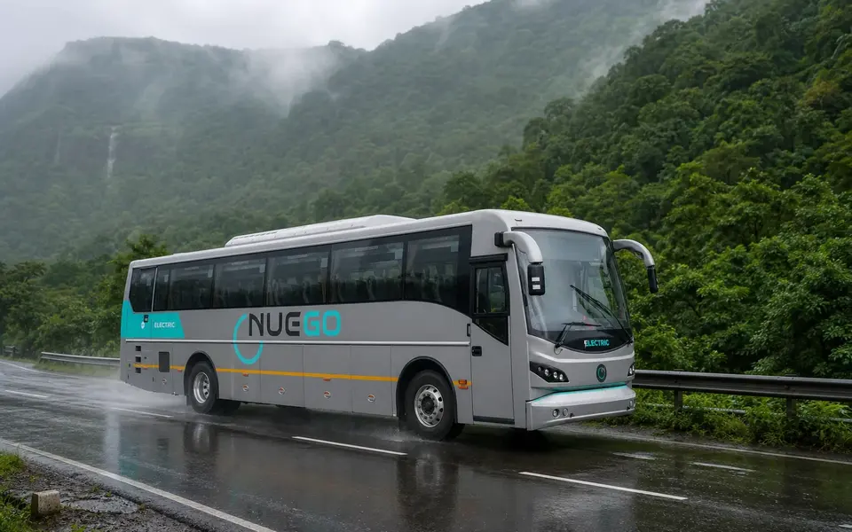 NueGo electric intercity coach travelling on a wet Indian highway during monsoon rain.