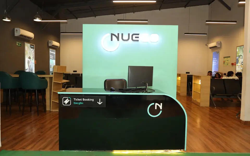 NueGo travel lounge interior with ticket counter, seating and guests waiting before a scheduled departure.