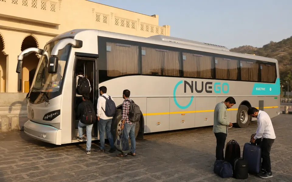 Travellers boarding a clearly branded NueGo electric intercity coach for a Rajasthan journey.