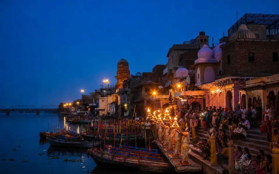 Evening Yamuna Aarti at Vishram Ghat in Mathura, showing priests, local riverside architecture and boats on the Yamuna.