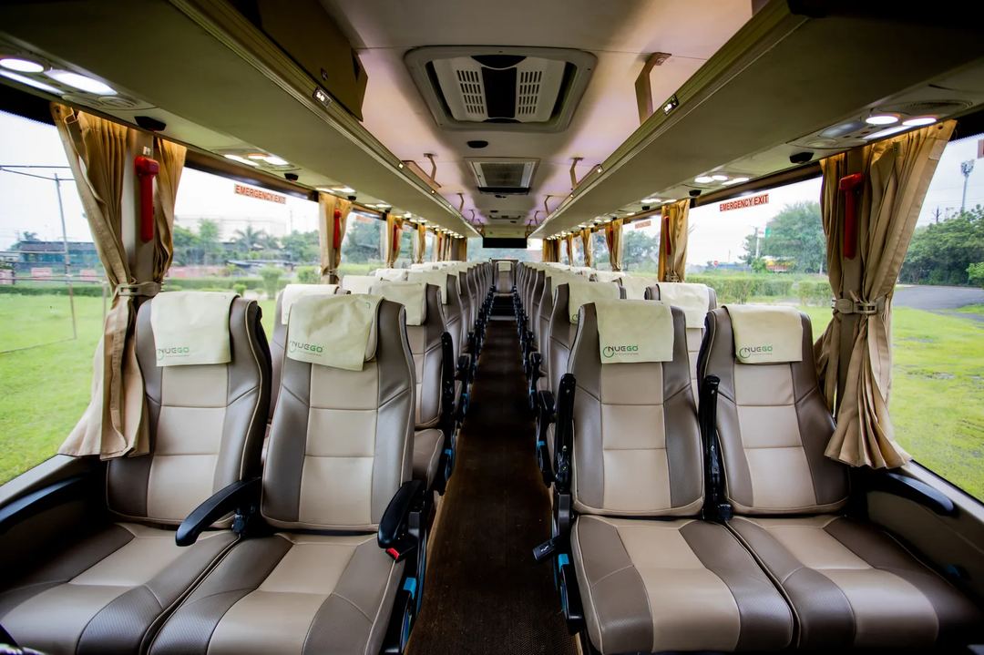 Wide view of a clean NueGo seater coach interior with reclining seats, overhead storage and a clear central aisle.