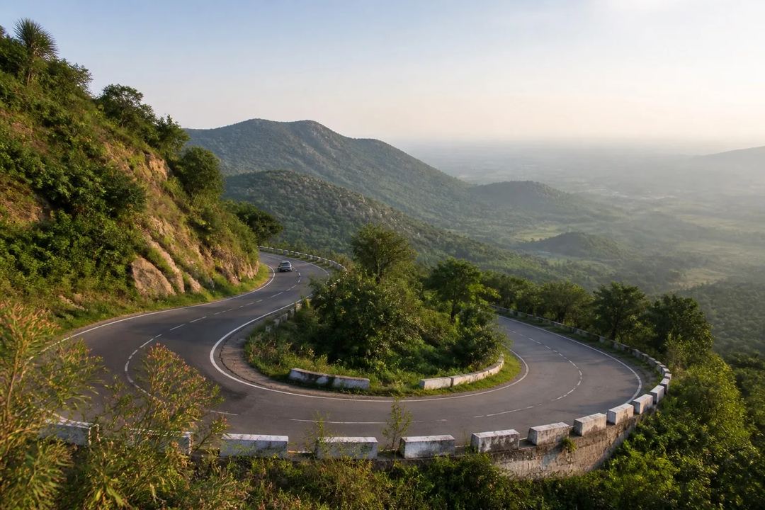 Reference-led landscape illustration of a sweeping hairpin bend on the green Eastern Ghats road to Yelagiri, with a hazy valley beyond.