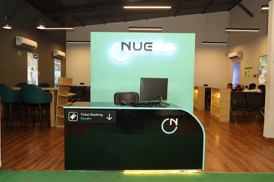 NueGo travel lounge interior with ticket counter, seating and guests waiting before a scheduled departure.