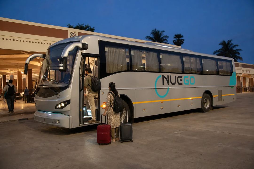 A couple boarding a clearly branded NueGo electric intercity coach for a Madurai journey.