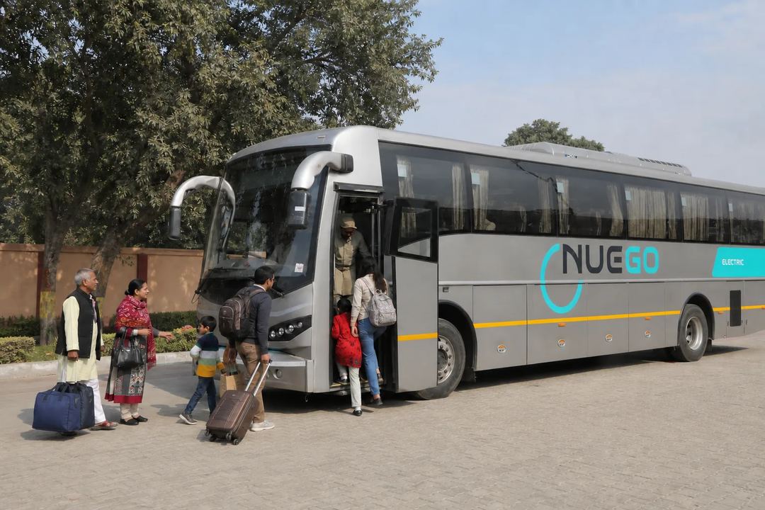 Clearly branded NueGo electric intercity coach travelling on an Indian highway, photographed from outside.